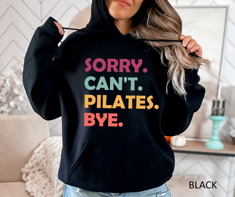 May include: Black hooded sweatshirt with the text "SORRY. CAN'T. PILATES. BYE." in colorful letters.