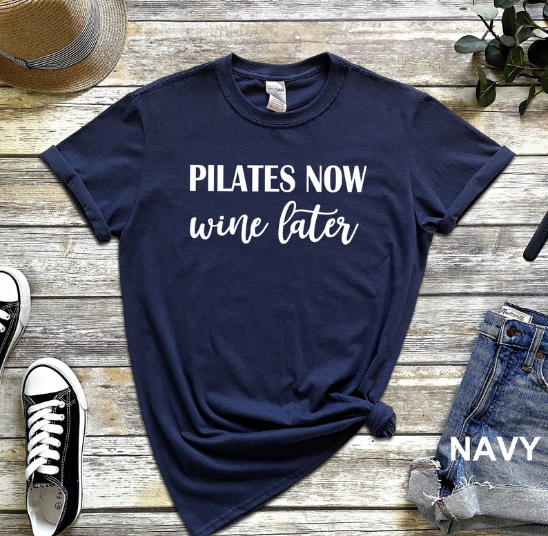 K&ouml;nnte beinhalten: Ein marineblaues T-Shirt mit wei&szlig;em Text, der "Pilates Now Wine Later" lautet.