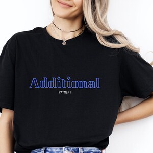 Op de afbeelding: Zwart T-shirt met de tekst "Additional Payment" in blauwe omrande letters.