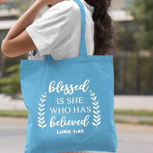 May include: Light blue tote bag with white text that reads "blessed is she who has believed" and "LUKE 1:45".