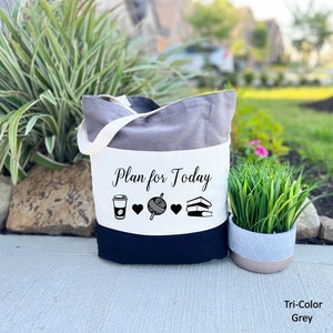 May include: A tri-color gray tote bag with a white panel that says "Plan for Today" and features icons of a coffee cup, yarn, and books.