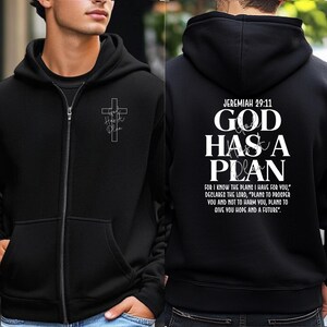 May include: Black zip-up hoodie with a white cross graphic and the words "God Has a Plan" on the back. The front features a smaller cross design with the words "Hope" and "Plan". The hoodie includes the Bible verse Jeremiah 29:11.