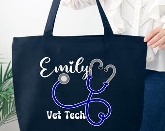 May include: Navy blue tote bag with white text reading "Emily" and "Vet Tech". A blue and gray stethoscope design is featured below the name. The bag has two navy blue handles.
