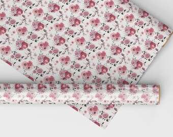 May include: A roll of white wrapping paper with a pink floral pattern. The paper is covered in a repeating pattern of pink roses, pink daisies, and green leaves.