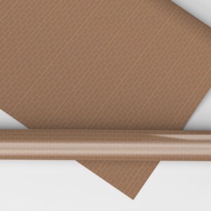 Könnte beinhalten: Eine Rolle brauner Tapete mit Ziegelmuster und ein teilweise abgerolltes Blatt. Die Tapete zeigt ein sich wiederholendes Ziegeldesign in Braun- und Beigetönen. Die Rolle ist zylindrisch und das Blatt rechteckig.