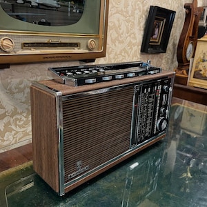 May include: Vintage brown and silver radio with a wood grain finish. The radio has a speaker grill, tuning dials, and a control panel. The radio is a classic piece of electronics.