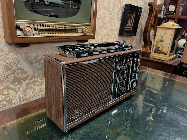 May include: Vintage brown and silver radio with a wood grain finish. The radio has a speaker grill, tuning dials, and a control panel. The radio is a classic piece of electronics.