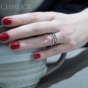 May include: A hand with red nail polish holds a gray and white mug. A silver ring with a detailed design is on the ring finger. The image has the text "ABASCHMUCK" at the top.