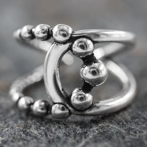 Puede incluir: Anillo de plata con un diseño único que presenta una serie de círculos interconectados y pequeñas esferas.