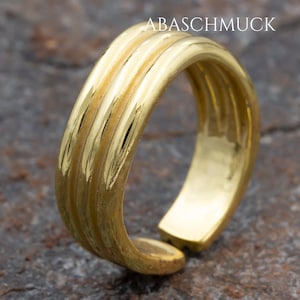 Op de afbeelding: Een gouden ring met drie verhoogde banden. De ring is open en heeft een gladde, gepolijste afwerking.