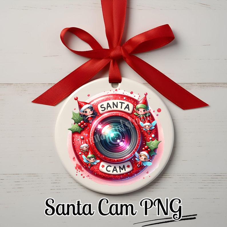 Puede incluir: Un adorno redondo de cer&aacute;mica blanca con un dise&ntilde;o de c&aacute;mara roja. La c&aacute;mara tiene una lente con un efecto arco&iacute;ris y las palabras "Santa Cam" escritas en ella. Hay peque&ntilde;os elfos alrededor de la c&aacute;mara, y las palabras "Santa Cam" est&aacute;n escritas en negro en la parte inferior del adorno.