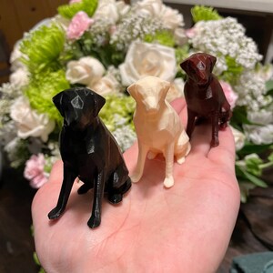 K&ouml;nnte beinhalten: Drei 3D-gedruckte Hundefiguren in verschiedenen Farben: Schwarz, Wei&szlig; und Braun. Die Figuren sitzen auf einer Hand.