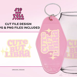 May include: A pink motel-style keychain with the words "CUTE BUT LIBRA" in a retro font, along with star accents. The design is also printed on a white background. A clear glass is in the background.