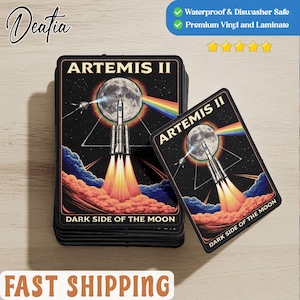 May include: Rectangular stickers featuring a space-themed design with the text "ARTEMIS II" and "DARK SIDE OF THE MOON." The design includes a rocket launching towards a full moon, a rainbow, and a starry background. The stickers are waterproof and made of premium vinyl.