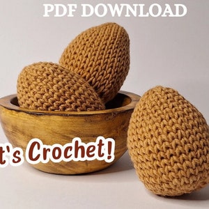 May include: Three crocheted brown eggs in a wooden bowl. The text "It's Crochet!" is written below the bowl.