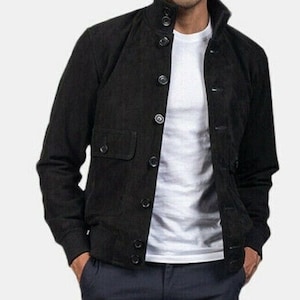 Puede incluir: Una chaqueta bomber de ante negro con cierre de botones y un bolsillo de solapa en el lado izquierdo.
