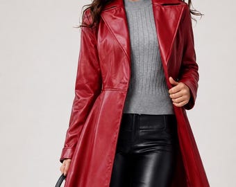 May include: A long red faux leather trench coat with a wide collar and button closure, worn over a grey ribbed mock neck sweater and black faux leather trousers, accompanied by a black handbag with top handles and a structured rectangular base.