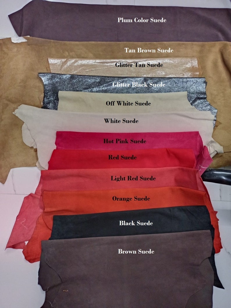 May include: A variety of suede leather swatches in different colors, including plum, tan brown, glitter tan, glitter black, off white, white, hot pink, red, light red, orange, black, and brown.