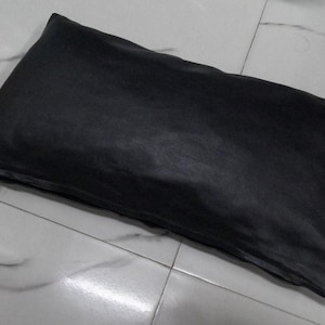 Puede incluir: Una almohada rectangular negra con cierre de cremallera.
