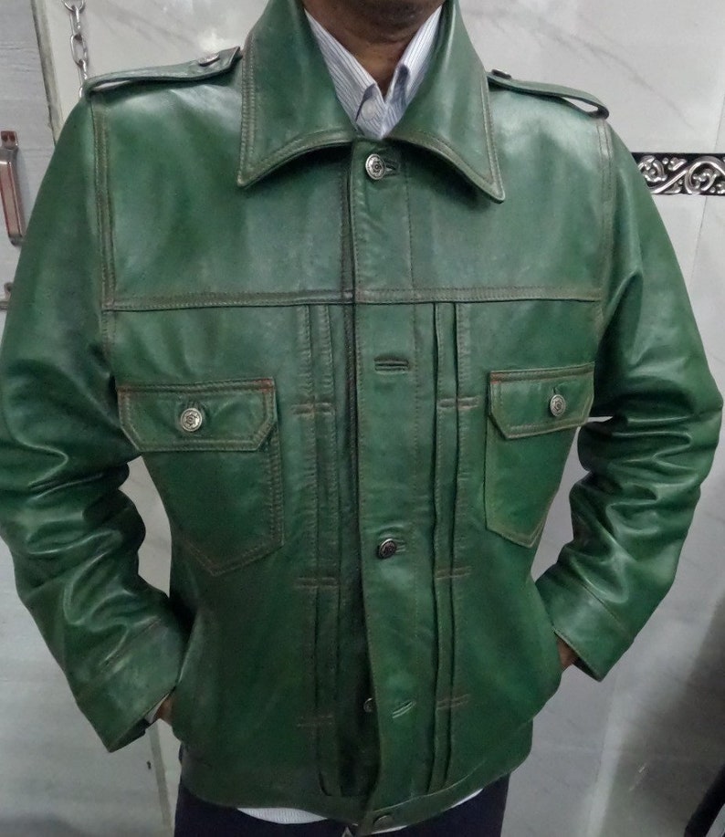 May include: A green leather jacket with a button-up front and two flap pockets. The jacket has a collar and long sleeves.