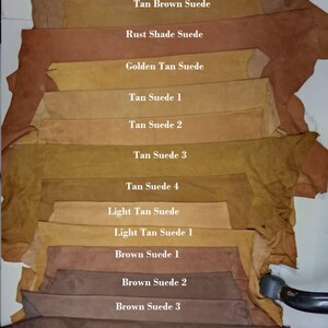 May include: A variety of suede leather swatches in different shades of brown, tan, and blue. The swatches are labeled with their color names, such as "Royal Blue Suede", "Tan Brown Suede", and "Light Tan Suede".