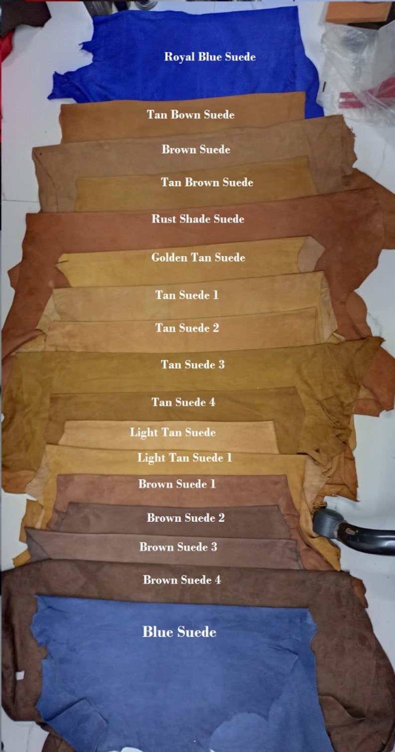May include: A variety of suede leather swatches in different shades of brown, tan, and blue. The swatches are labeled with their color names, such as "Royal Blue Suede", "Tan Brown Suede", and "Light Tan Suede".