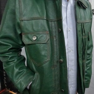 May include: A green leather jacket with a button-up front and multiple pockets. The jacket has a collar and long sleeves.