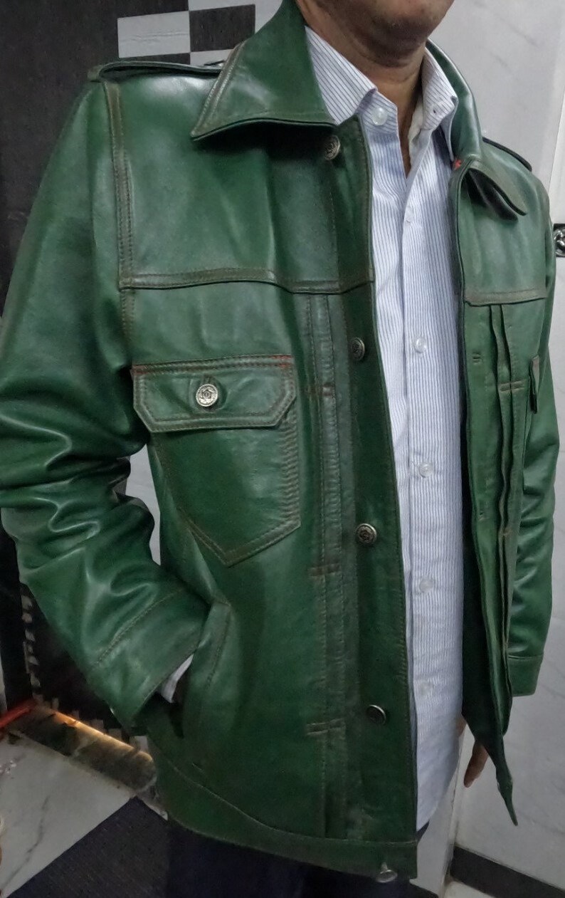 May include: A green leather jacket with a button-up front and multiple pockets. The jacket has a collar and long sleeves.