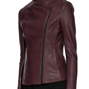 May include: A burgundy leather jacket with a zipper closure and a diagonal seam detail. The jacket has a stand-up collar and long sleeves.
