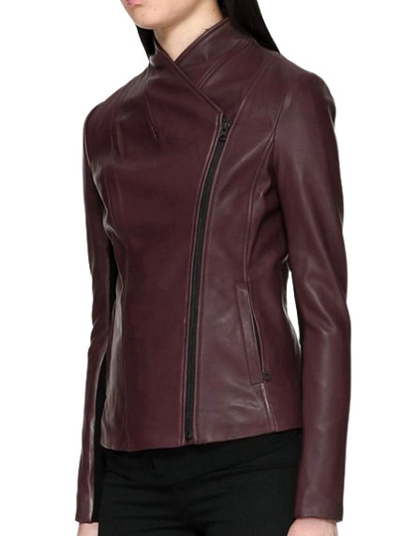May include: A burgundy leather jacket with a zipper closure and a diagonal seam detail. The jacket has a stand-up collar and long sleeves.