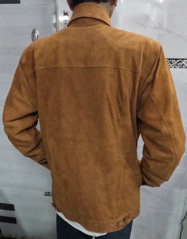 May include: A brown suede jacket with a button-up front and long sleeves.