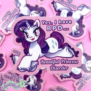 May include: A pink sticker featuring a cartoon pony with a white body, purple mane, and a unicorn horn. The sticker has text that reads "Yes, I have BPD..." and "Beautiful Princess Disorder."