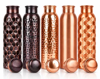 Puede incluir: Cinco botellas de agua cilíndricas de metal con tapas de rosca a juego. Las botellas presentan texturas variadas que incluyen patrones hexagonales de panal, acabados martillados y una superficie lisa pulida en tonos cobre y marrón.
