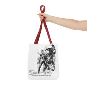 May include: White tote bag with a black and white illustration of a German Shorthaired Pointer dog. The bag has dark red handles and includes text that reads "10% bird dog, 90% unregulated kinetic energy. THE GERMAN SHORTHAIRED POINTER."