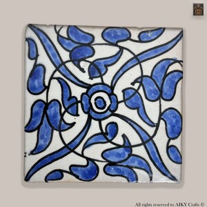 Peut inclure: Un carreau de céramique carré avec un motif floral bleu et blanc. Le carreau présente des motifs en spirale complexes et des feuilles stylisées.