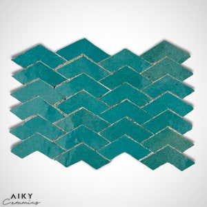 Może przedstawiać: Turkusowe ceramiczne płytki mozaikowe ułożone w jodełkę. Płytki są małe i mają lekko fakturowaną powierzchnię.