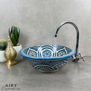May include: A blue and white ceramic sink with intricate Moroccan-inspired patterns. The sink is round and has a wide rim. A chrome faucet is visible in the background.