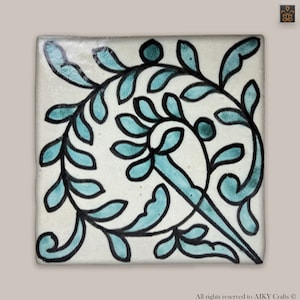 Peut inclure: Un carreau de céramique blanc avec un motif floral bleu et noir. Le motif présente un motif tourbillonnant de feuilles et de tiges.