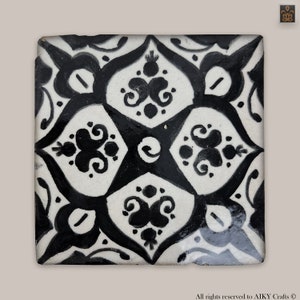 Peut inclure: Carreau de céramique noir et blanc avec un motif géométrique. Le carreau présente un motif répétitif de fleurs stylisées et de volutes.