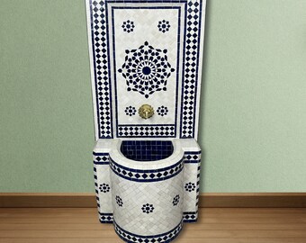 May include: A white and blue Moroccan style tiled fountain with a basin and a brass faucet. The fountain has a geometric design with a central starburst.
