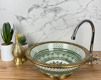 May include: A green and white ceramic sink with a gold rim and intricate geometric patterns. The sink is set on a wooden countertop with a chrome faucet.