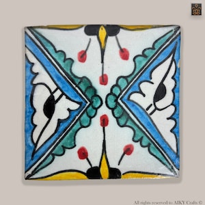Peut inclure: Un carreau de céramique carré avec un motif géométrique. Le carreau est décoré de peinture bleue, verte, jaune, noire et rouge. Le motif présente des motifs floraux stylisés et un losange central.