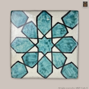 Peut inclure: Carreau de céramique carré avec un motif géométrique. Le carreau présente un fond blanc avec un motif en étoile de couleur sarcelle et noir. Le motif est symétrique et le carreau a une finition brillante. Le carreau est probablement destiné à un usage décoratif.