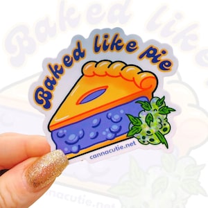May include: A sticker with a cartoon illustration of a slice of blueberry pie with the text "Baked like pie" in a purple and yellow color scheme. The sticker also includes a green leaf with a white background.