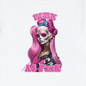 Peut inclure: T-shirt blanc avec un motif rose et noir d'une femme aux cheveux roses et au visage de crâne. Le texte "PINK AS F*CK" est imprimé en rose sous le motif.