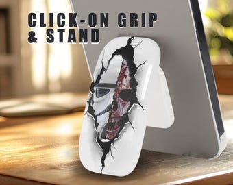 May include: White phone grip and stand with a graphic of a cracked wall revealing a zombie skull and a Star Wars Stormtrooper helmet. The text "CLICK-ON GRIP & STAND" is printed on the top of the image.