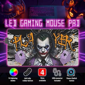 Puede incluir: Alfombrilla de ratón LED para juegos con diseño de Joker. La alfombrilla tiene un fondo negro con un gráfico "PLAYER" blanco y naranja, un gráfico de carta de juego púrpura y una imagen de Joker. La alfombrilla tiene 14 modos de iluminación, una base de goma antideslizante y un conector USB.