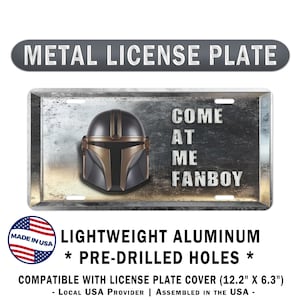 May include: Metal license plate featuring a Mandalorian helmet design with the text "COME AT ME FANBOY." The plate is made of lightweight aluminum and has pre-drilled holes. The plate is compatible with a license plate cover, measuring 12.2 inches by 6.3 inches.