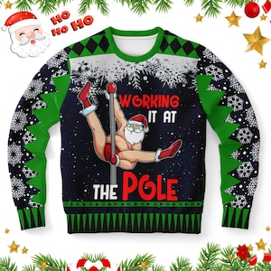 Könnte beinhalten: Ein dunkelblaues Langarm-Sweatshirt mit einer Grafik des Weihnachtsmanns, der an einer Stange tanzt. Der Text lautet Working it at the Pole. Das Kleidungsstück zeigt grüne und schwarze geometrische Muster, weiße Schneeflocken und rote Akzente.