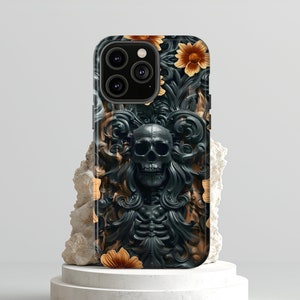 May include: Black phone case featuring a detailed skull design with floral accents. The case has a dark, gothic aesthetic with a carved appearance. The flowers are a warm orange color.